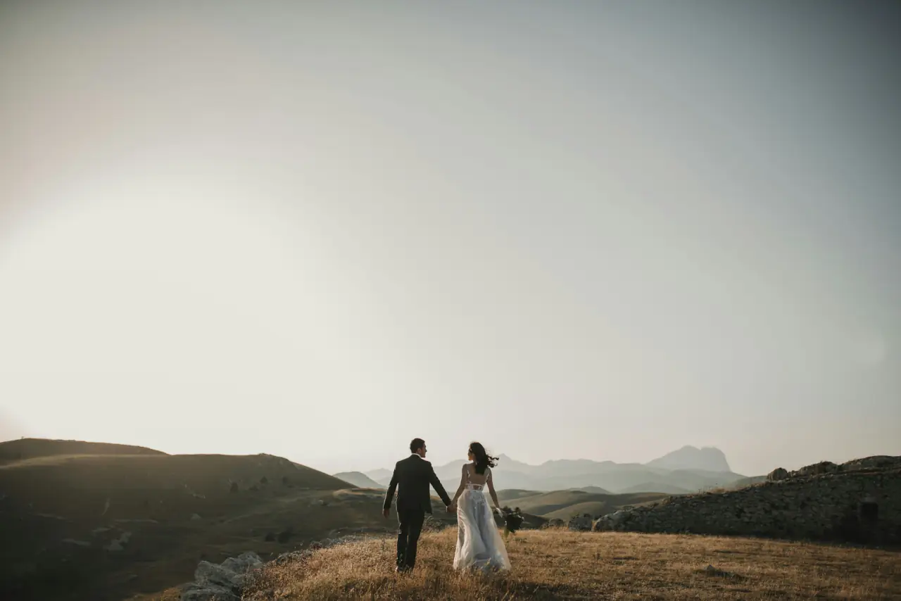 Bride and groom walking across the hills at sunrise